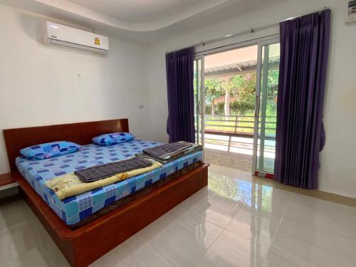 a bedroom with a bed and a sliding glass door at Firdous Guesthouse in Ban Khlong Hia