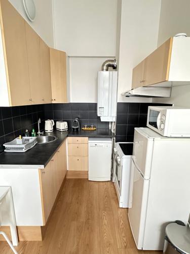 a kitchen with white appliances and black tiles at Jade Apart Bussy Centre Disney 10min in Bussy-Saint-Georges