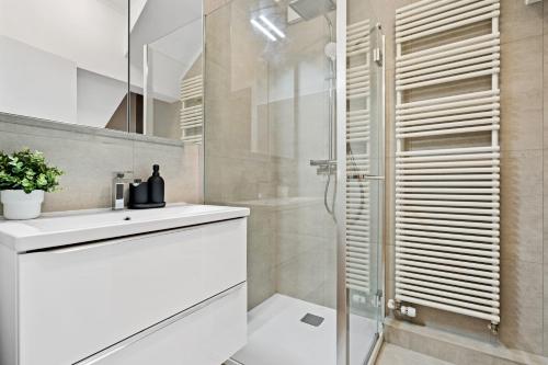 a white bathroom with a sink and a shower at Comfortable 2BR Apt in Prime Luxembourg Location in Luxembourg