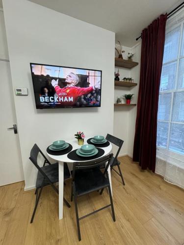a dining room with a table and a tv on the wall at Kings Cross-Euston Apartment in London