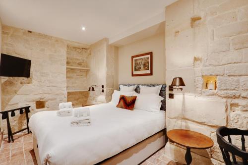 a bedroom with a large white bed and a stone wall at Pick A Flat's Apartments in Saint Germain - Paul-Louis Courier in Paris