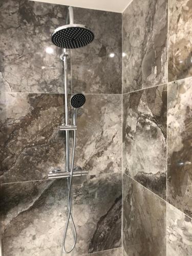 La salle de bains est pourvue d'une douche et d'un mur en pierre. dans l'établissement Appartement RDC dans une Villas, à Montpellier