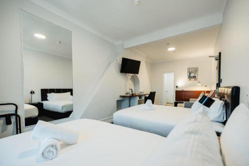 a hotel room with two beds and a television at Newtown Cozy Stays in Sydney