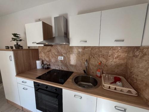 a kitchen with white cabinets and a sink at Apartment Mandy in Rečica ob Savinji