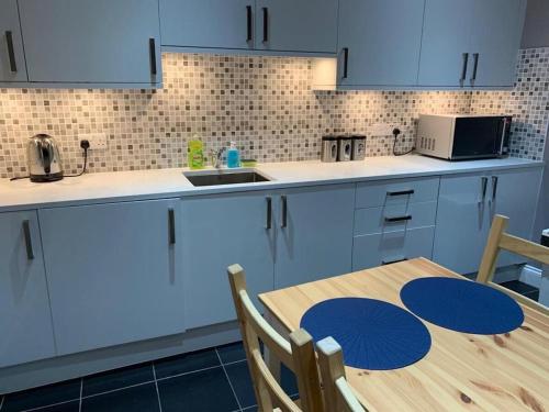 a kitchen with blue cabinets and a wooden table at Wood Green Rooms in London