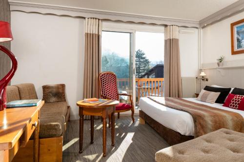 a hotel room with a bed and a couch and a table at Hôtel & Spa Les Bartavelles in Crots