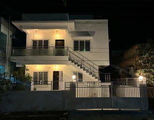 a white house with a staircase in front of it at night at White Haven Homestay in Alibag