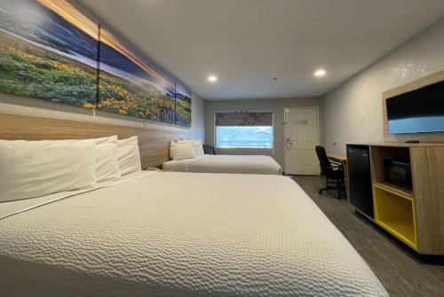 a hotel room with two beds and a flat screen tv at Days Inn by Wyndham Near Seaworld San Antonio in San Antonio