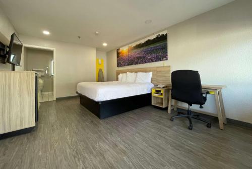 a hotel room with a bed and a desk and a chair at Days Inn by Wyndham Near Seaworld San Antonio in San Antonio