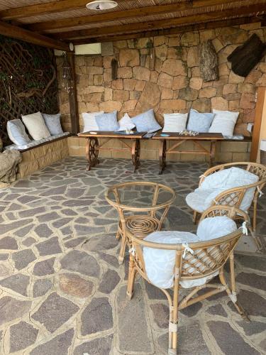 a patio with a table and chairs and a stone wall at Lulamax Sardegna in Budoni
