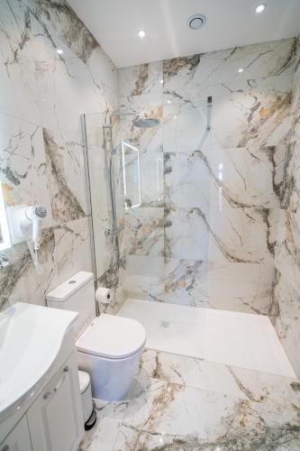 a white bathroom with a toilet and a shower at L-Eremita Boutique Hotel in Qala
