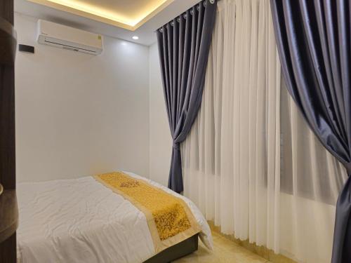 sypialnia z łóżkiem i oknem z zasłonami w obiekcie 4L HOTEL KIM BÔI w mieście Làng Trang