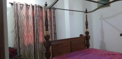 uma cama com uma cabeceira de madeira e uma cortina em Villa Ocean Breeze em Ambalangoda