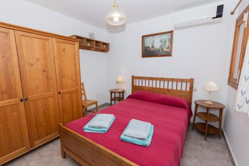 a bedroom with a bed with red sheets and wooden cabinets at Yourhouse Villa Sa Caseta in Llubí