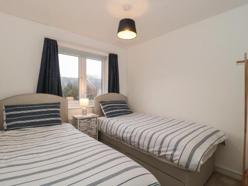two beds in a room with a window at Sandy Toes in Christchurch