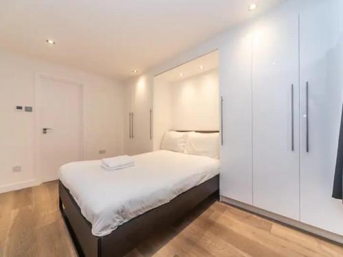 a white bedroom with a large bed and white cabinets at Pass the Keys Spacious flat in Shoreditch in London