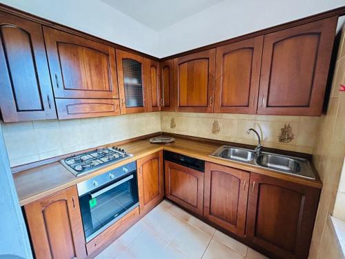a small kitchen with wooden cabinets and a sink at Budoni Beach Apartments in Budoni