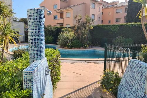 Elle offre une vue sur une piscine entourée d'une clôture et de plantes. dans l'établissement Boulouris - Appt 3/4 pers. bord de mer / piscine, à Saint-Raphaël