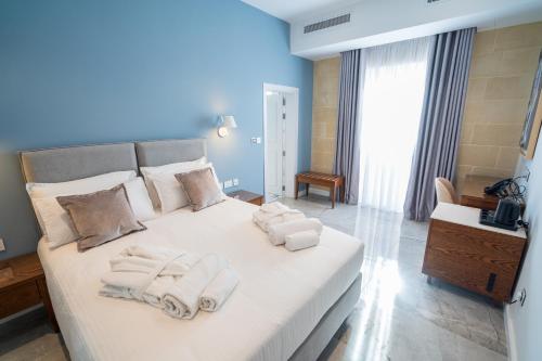 a bedroom with a large white bed with towels on it at L-Eremita Boutique Hotel in Qala