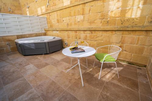 a table and chairs in front of a brick wall at L-Eremita Boutique Hotel in Qala