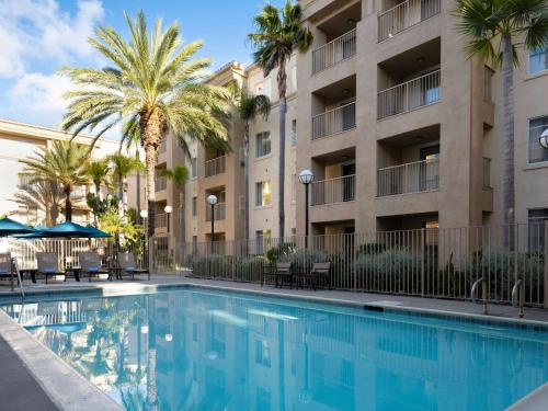 a swimming pool in front of a building with palm trees at Hyatt House San Diego Sorrento Mesa in Sorrento