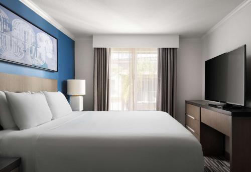 une chambre d'hôtel avec un grand lit et une télévision dans l'établissement Hyatt House San Diego Sorrento Mesa, à Sorrento