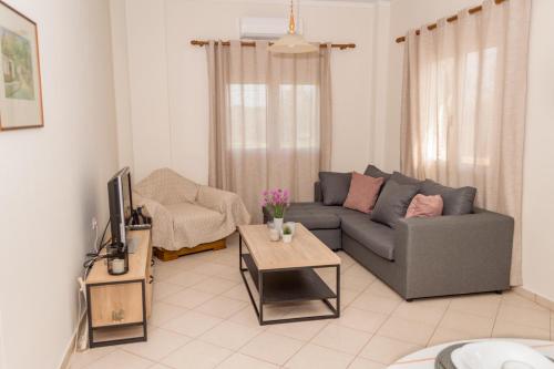 a living room with a couch and a tv at Olivia House -BY APOKORNAS VILLAS in Káïna