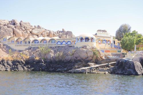 a large building on a cliff next to the water at Old Nubian guest house in Aswan