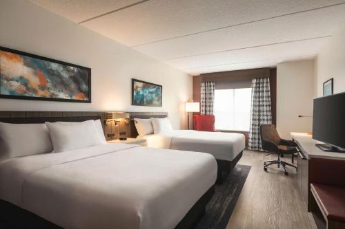 ein Hotelzimmer mit 2 Betten und einem Schreibtisch in der Unterkunft Hilton Garden Inn Palm Coast Town Center in Palm Coast
