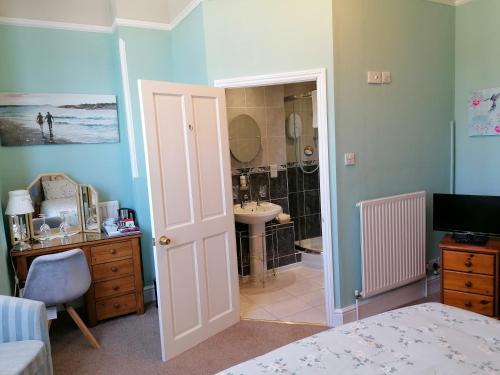 a bedroom with a bathroom with a sink and a shower at Pebbles House in Seaton