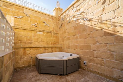 a bathroom with a bath tub in a brick wall at L-Eremita Boutique Hotel in Qala