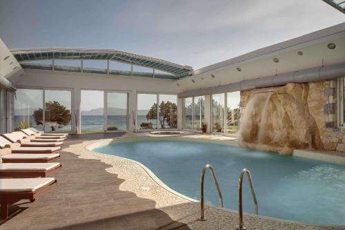 - une piscine avec des chaises longues et un complexe dans l'établissement Barceló Hydra Beach, à Thermisía