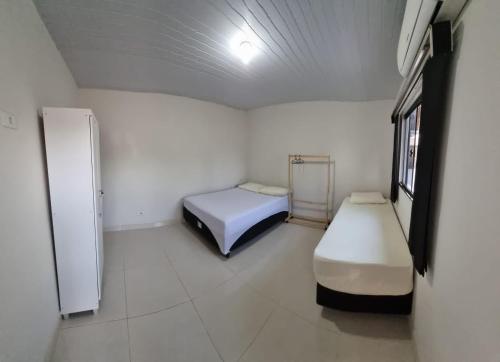 um pequeno quarto com 2 camas e um frigorífico em Recanto das Araras, Transcendental em Bonito