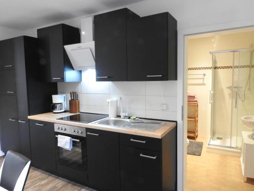 a kitchen with black cabinets and a sink at Ferienwohnungen am Hauptplatz in Pirna