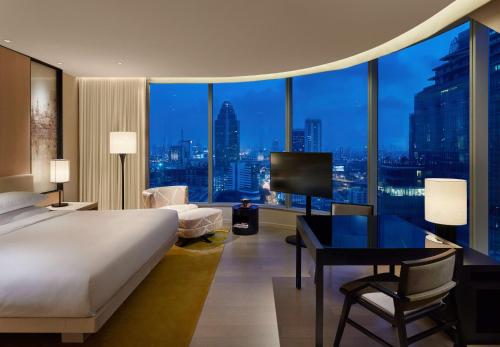 sypialnia z łóżkiem, biurkiem i dużym oknem w obiekcie Park Hyatt Bangkok w mieście Bangkok