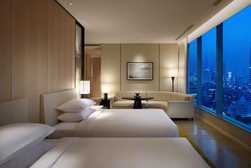 a hotel room with two beds and a couch at Park Hyatt Bangkok in Bangkok
