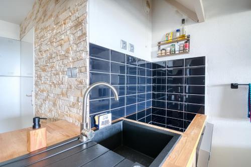 a kitchen with a sink and a brick wall at Soleil du Crouesty - garage et piscine partagée in Arzon