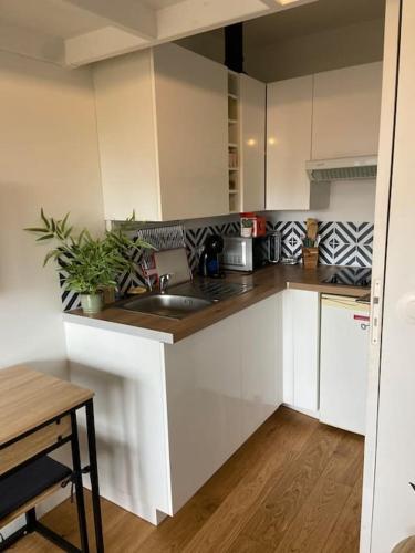 - une cuisine avec des placards blancs, un évier et une table dans l'établissement studio Biscarrosse plage, à Biscarrosse