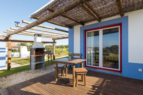 een houten terras met een tafel en een grill bij Monte do Cerro in Porto Covo