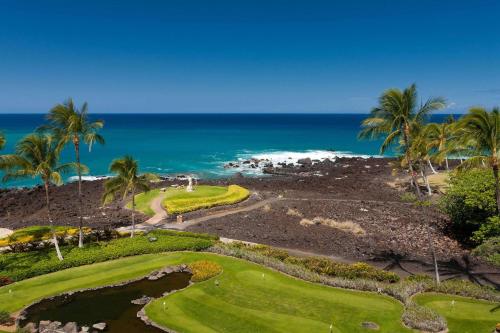 an aerial view of a golf course with palm trees and the ocean at Hilton Grand Vacations Club Ocean Tower Waikoloa Village in Waikoloa