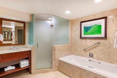 a bathroom with a tub and a sink and a shower at Hilton Grand Vacations Club Ocean Tower Waikoloa Village in Waikoloa