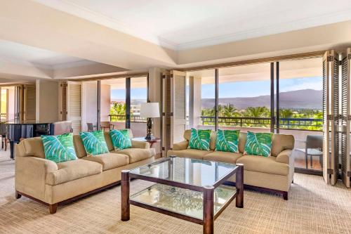 a living room with two couches and a glass table at Hilton Grand Vacations Club Ocean Tower Waikoloa Village in Waikoloa