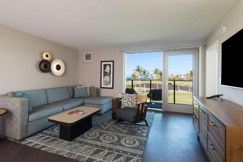 a living room with a blue couch and a tv at Hilton Grand Vacations Club Ocean Tower Waikoloa Village in Waikoloa