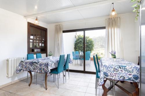 a dining room with two tables and blue chairs at Finca Los Geranios in Tegueste
