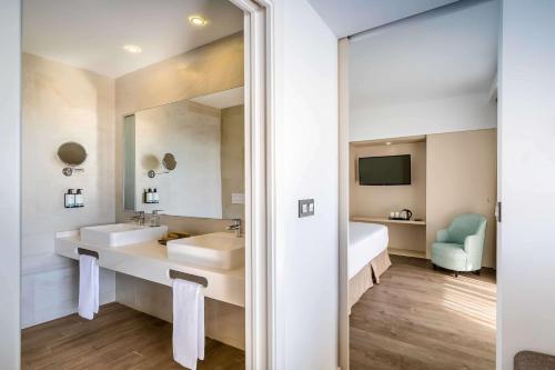 a bathroom with two sinks and a bed and a mirror at Occidental Fuengirola in Fuengirola