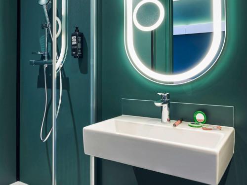 W łazience znajduje się biała umywalka i lustro. w obiekcie Ibis Montlhery Paris Sud w mieście Montlhéry