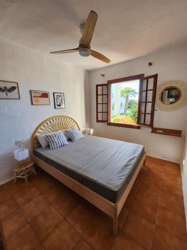 a bedroom with a bed with a ceiling fan at Charmant appartement vue mer in Fornells