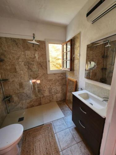 a bathroom with a sink and a toilet and a window at Charmant appartement vue mer in Fornells