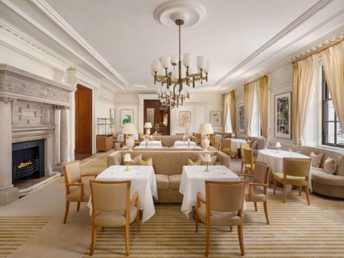 a dining room with tables and chairs and a fireplace at Raffles London at The OWO in London