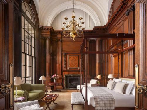 a bedroom with a bed and a fireplace and a chandelier at Raffles London at The OWO in London